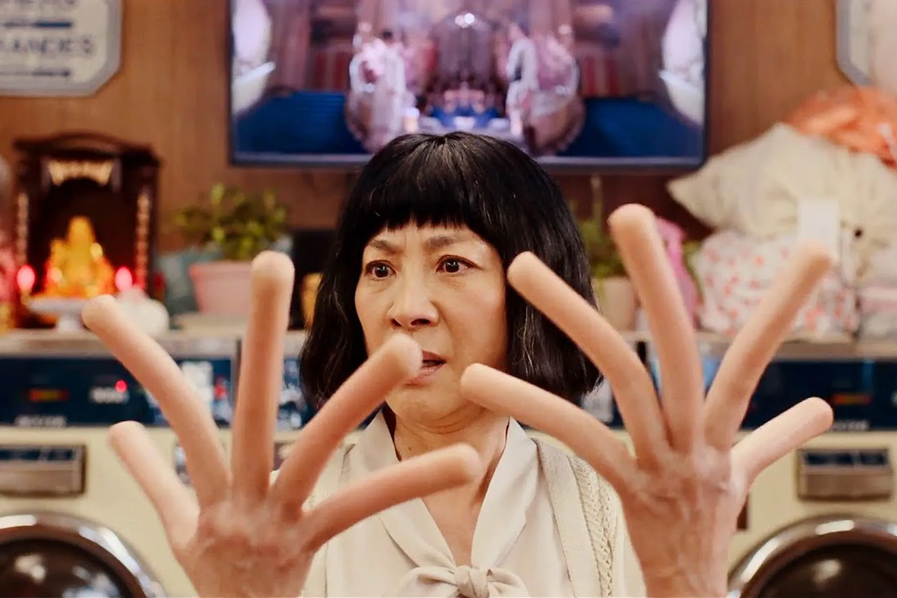 An older chinese woman stares at her own hands she's holding up in front of her which feature hot dogs instead of her fingers fingers